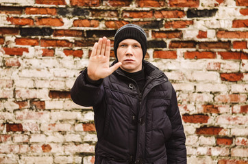 the guy shows a stop gesture. prohibition sign. Brick wall