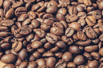 Many roast brown coffee grains texture close up on an abstract background
