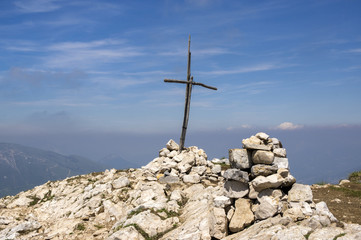 Fototapeta na wymiar Cima delle Pozzette, wooden cross on the top of a mountain, touristic trail Alta Via del Monte Baldo