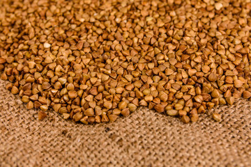 Pile of the raw buckwheat on sackcloth
