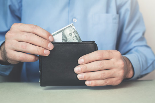 Businessman putting money into wallet.