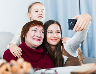 Smiling woman making selfie with mother and daughter