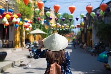 Tourist woman is wearing Non La (Vietnamese tradition hat) and enjoy sightseeing at Heritage village in Hoi An city in Vietnam.