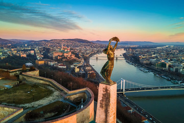 Fototapeta premium Budapest, Hungary - Aerial skyline view of Statue of Liberty with Buda Castle Royal Palace and Chain Bridge at background. Morning sunrise with blue sky and clouds