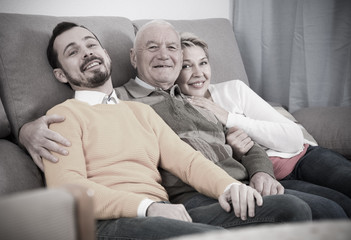 Smiling family hugging sitting on sofa