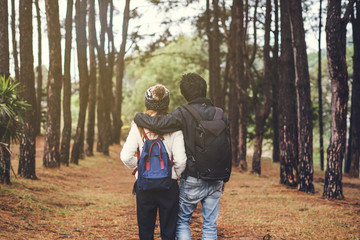 Young couple traveler with backpack walking together in the forest