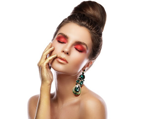 Beautiful woman with a colorful makeup is wearing earrings with green emeralds