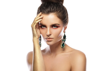 Beautiful woman with a colorful makeup is wearing earrings with green emeralds