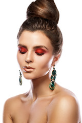 Beautiful woman with a colorful makeup is wearing earrings with green emeralds