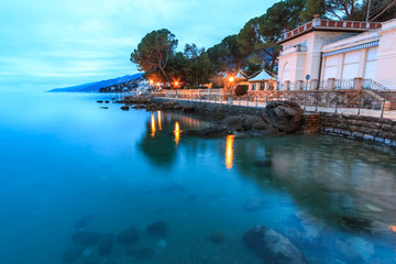 Obraz premium Lights of the Croatian costal city Opatija reflecting in the sea on the winter morning