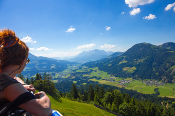 Fototapeta na wymiar eine Urlauberin sieht sich in Tirol ( Österreich ) bei Sonnenschein die Landschaft an