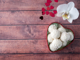 Coconut candy in a red heart Orchid Flower Wooden Background Copy space
