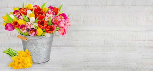 Frühling - Tulpen und Narzissen mit Eimer und Dekoration auf Holz