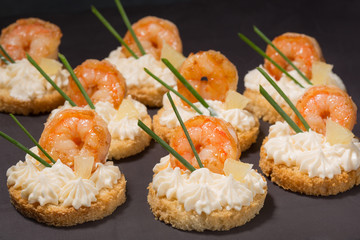canapé with shrimp on white bread, decorated with a slice of lemon, on a black slide