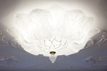 A beautiful glass lamp on the ceiling with stucco molding.