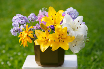 Bouquet of yellow and white lilies and lilac phlox on the meadow.