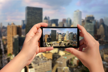 Female hand with mobile phone take picture of midtown of Manhattan on sunset. Plane flies over skyscrapers of New York City, Manhattan.