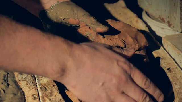 Hands take out half dried clay from inside a form. 