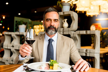 Handsome man drinking red wine during lunch