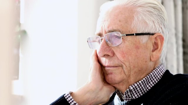 Worried Senior Man Sitting In Chair At Home