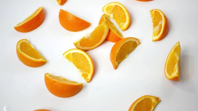 Sliced Orange wedges spinning over white background - Overhead view