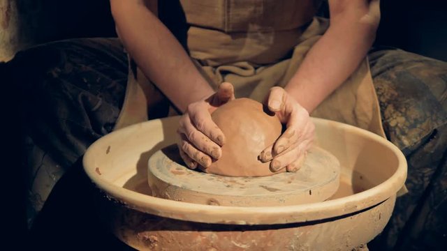 Potters hands put clay on a wheel. 