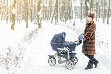 Woman walking with stroller in forest at winter.