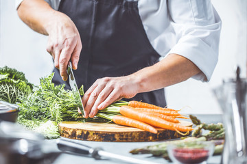 Chefkoch in der Küche mit Frischem Gemüse(Karotten)