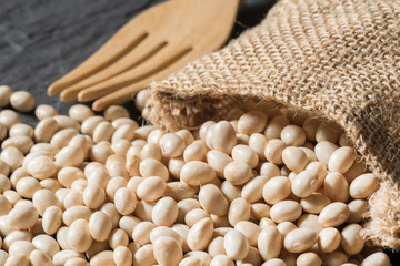 Stack of white bean with burlap bag on table, Close-up dried soybean with sack cloth