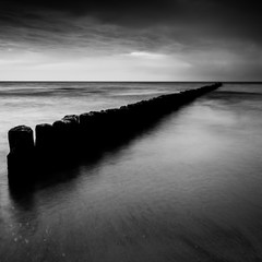 coucher de soleil sur la mer avec une jetée en bois, photo noir et blanc, longue exposition