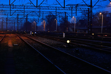 Fototapeta na wymiar Tory kolejowe, semafory, sygnalizatory wieczorem i lekka mgła/