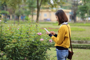 スマートフォンで花の写真を撮影する女性