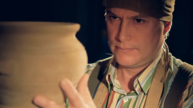 A potters face as he twists a bowl in his hands. 