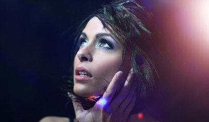 Beautiful black-haired woman with peacock feathers in studio sho