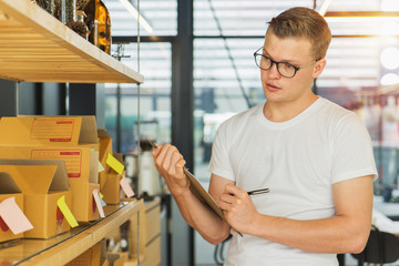 Obraz premium Young man with clipboard checking orders at warehouse