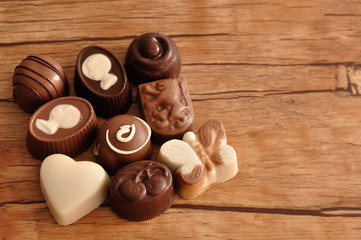 A variety of small chocolates on a wooden background