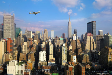 Obraz premium View of midtown of Manhattan on sunset. Plane flies over skyscrapers of New York City, Manhattan