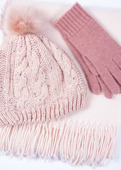 Warm winter knitted clothes - hat, scarf, gloves on a white background.