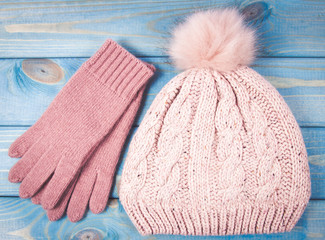 Warm winter knitted clothes - hat, gloves on a blue background.