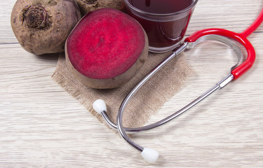 Healthy beetroot juice and fresh vegetables on wooden background.