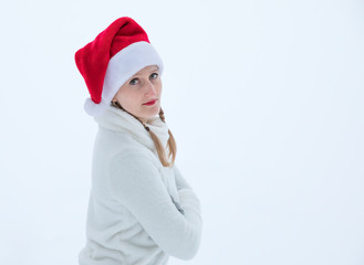 Young girl with knitted pants and red santa hat having fun on a white snowy winter day. Ruka, Finland.