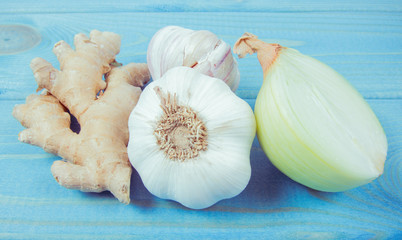 Garlic bulbs, ginger and onion on blue wooden table. Natural medicine.