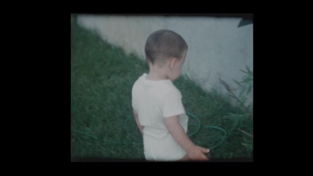 1961 2 year old little boy turns on water garden hose