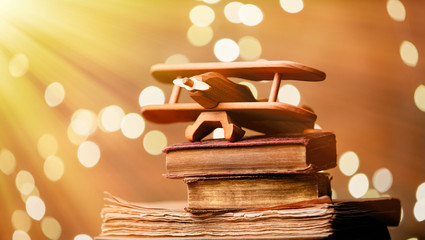 Vintage books and wooden plane with fairy lights