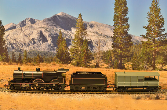 A model of a 4-4-0 locomotive in black wartime paint set on a scenic background