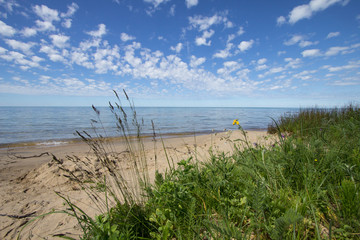 Scenic Sandy Beach Background. Sunny and sandy beach with dune grass in the foreground and a beautiful blue sky at waters horizon. Lake Michigan, Upper Peninsula, USA.