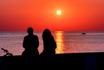 Fototapeta na wymiar Summer. Sea. Sunset on the Black sea. Sochi. Krasnodar Krai. Russia. Couple admiring the sunset on the beach.