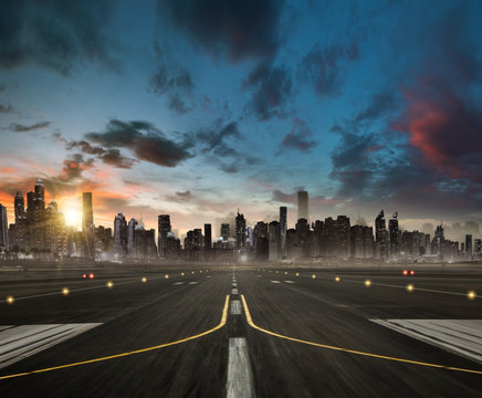 Empty airplane runway heading for the modern city with skyscrapers silhouettes.