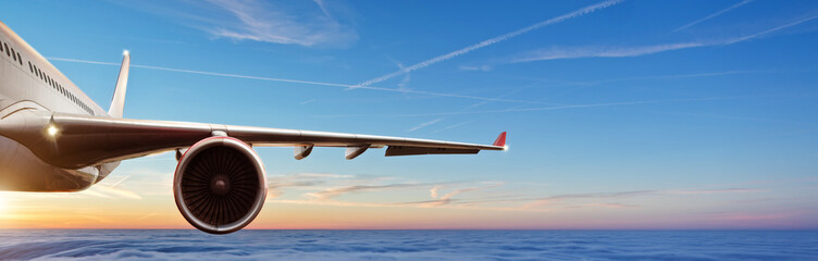 Fototapeta premium Szczegół skrzydło komercyjnego samolotu odrzutowiec lata above chmury w pięknym zmierzchu świetle.