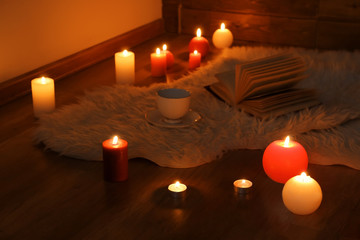 Burning candles on floor in dark room